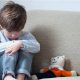 Image of A Sad Little and Boy and Teddy Bear Sitting on the Sofa in a Room