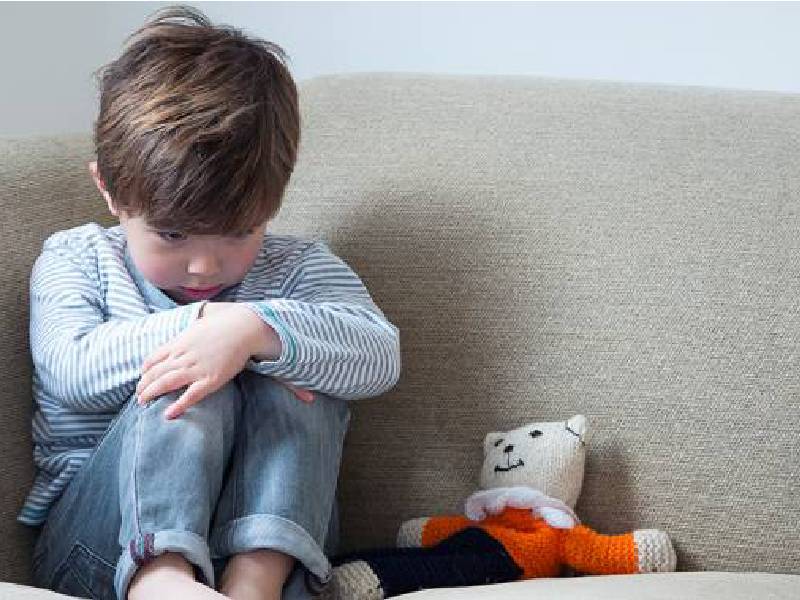 Image of A Sad Little and Boy and Teddy Bear Sitting on the Sofa in a Room